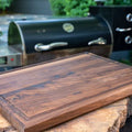 Knifz walnut cutting board on a rustic log slab outdoors